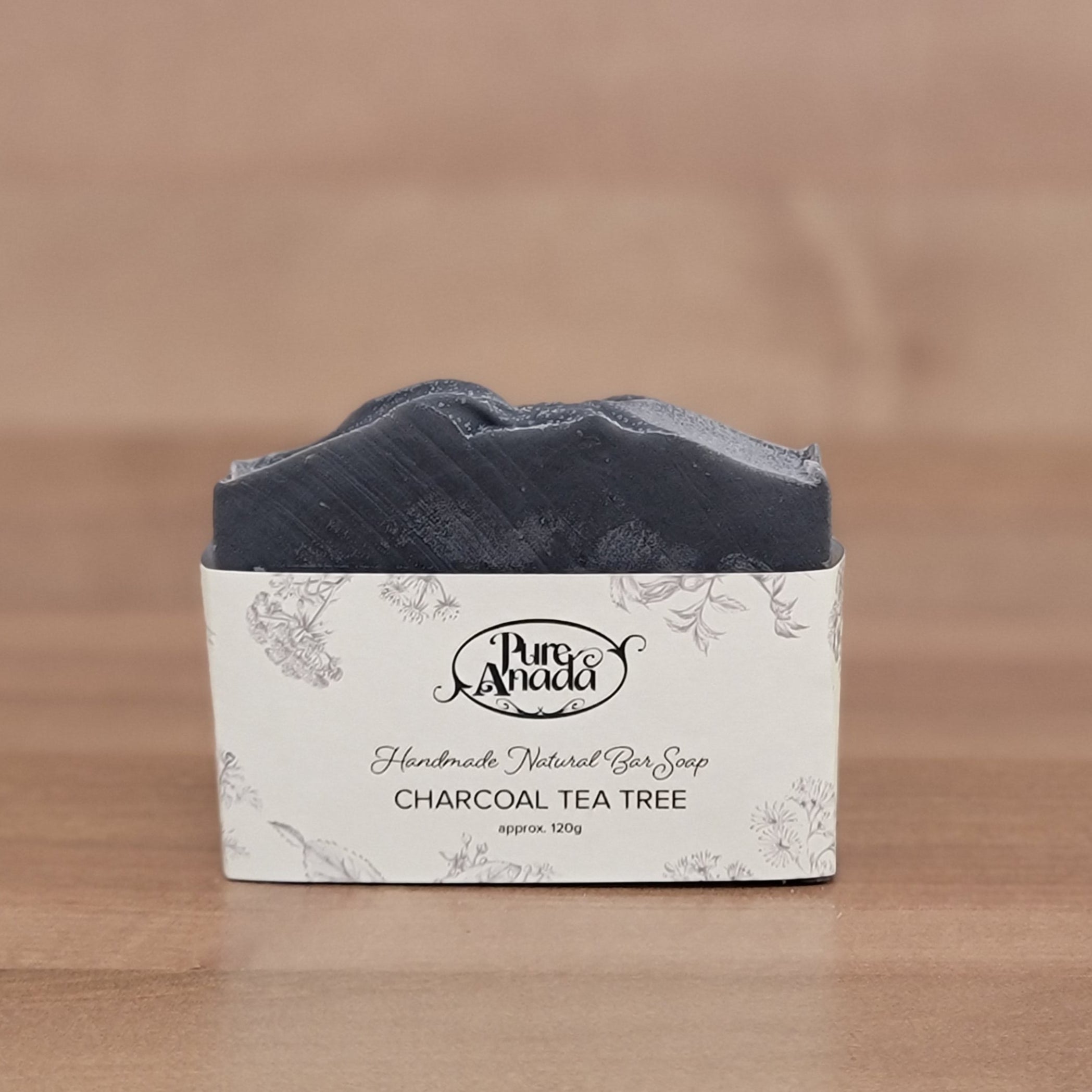Bar of charcoal tea tree soap with a label on a wooden surface